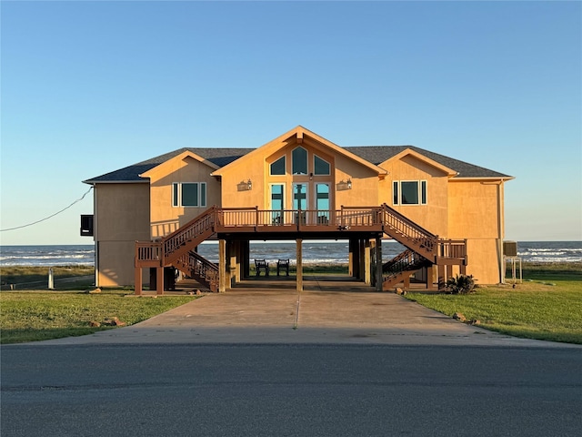 view of front facade featuring stairs, roof with shingles, concrete driveway, a front lawn, and a carport