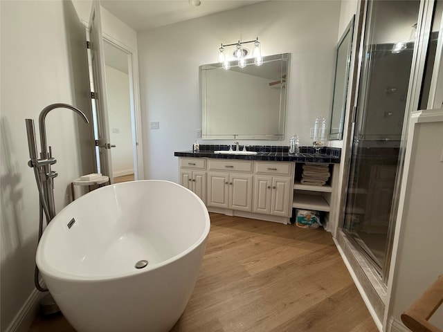 full bathroom featuring a shower stall, a freestanding bath, wood finished floors, and vanity