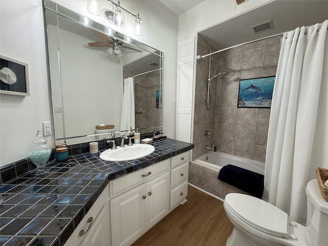 bathroom with wood finished floors, toilet, shower / tub combo with curtain, and a ceiling fan