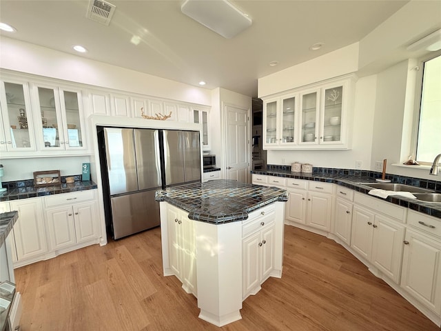 kitchen with visible vents, stainless steel appliances, a sink, light wood-type flooring, and a center island