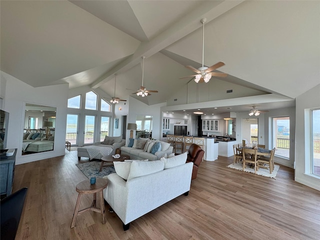 living room featuring high vaulted ceiling, beam ceiling, light wood-style flooring, and ceiling fan