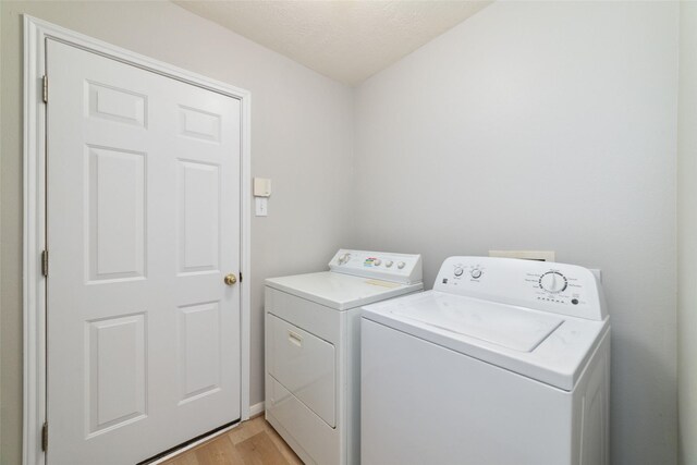 7014 Woodland Oaks, Magnolia, TX 77354 - laundry area with independent washer and dryer, light wood finished floors, and a textured ceiling