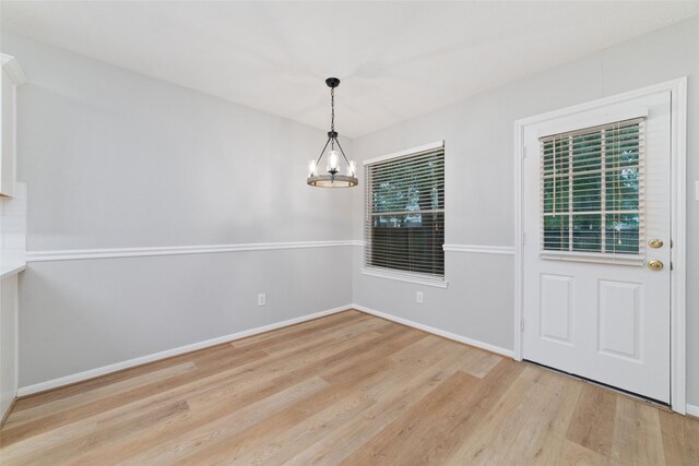7014 Woodland Oaks, Magnolia, TX 77354 - unfurnished dining area with a chandelier, light wood-style floors, and baseboards