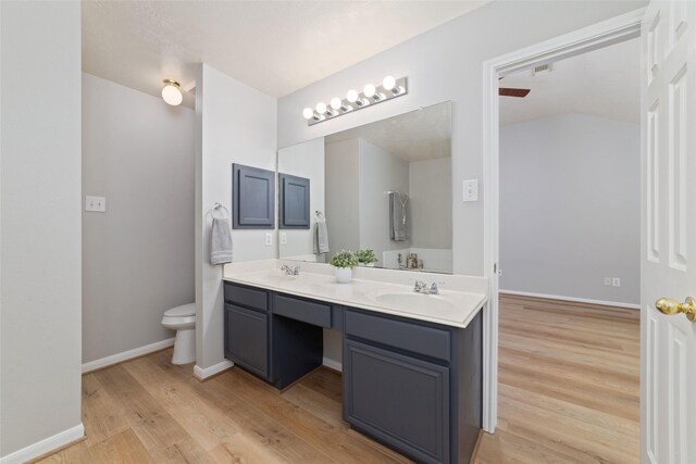 7014 Woodland Oaks, Magnolia, TX 77354 - bathroom featuring wood finished floors, double vanity, toilet, and baseboards