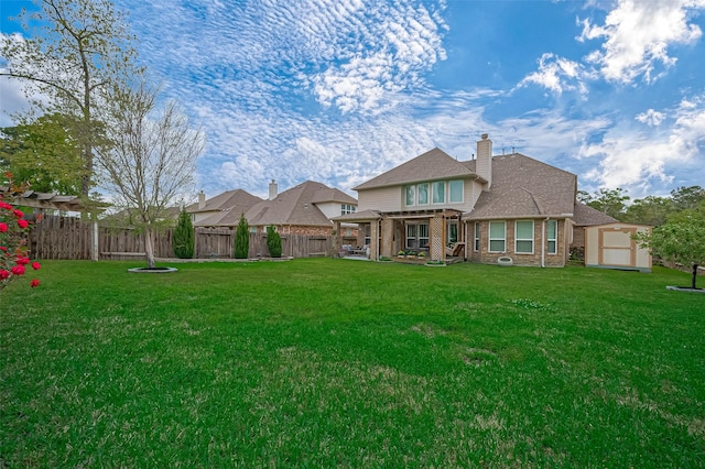 rear view of house with a chimney, a lawn, fence private yard, and brick siding