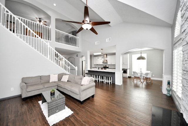 living area featuring dark wood finished floors, arched walkways, and stairway