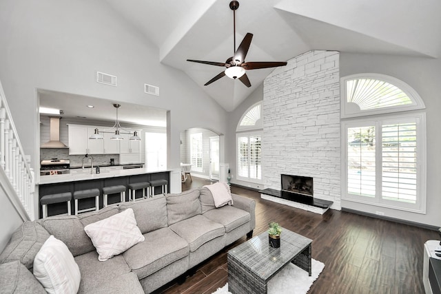 living area featuring a healthy amount of sunlight, visible vents, ceiling fan, and dark wood-style flooring