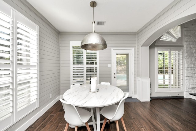 dining area with arched walkways, baseboards, visible vents, and dark wood finished floors
