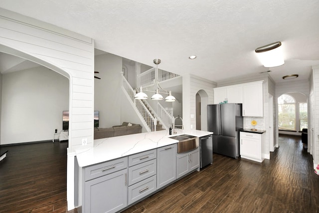 kitchen featuring dark wood-style floors, a sink, arched walkways, and appliances with stainless steel finishes