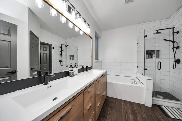 full bath featuring a bath, a sink, a stall shower, and wood finish floors