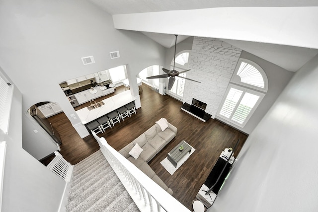 living room featuring high vaulted ceiling, visible vents, a ceiling fan, and wood finished floors