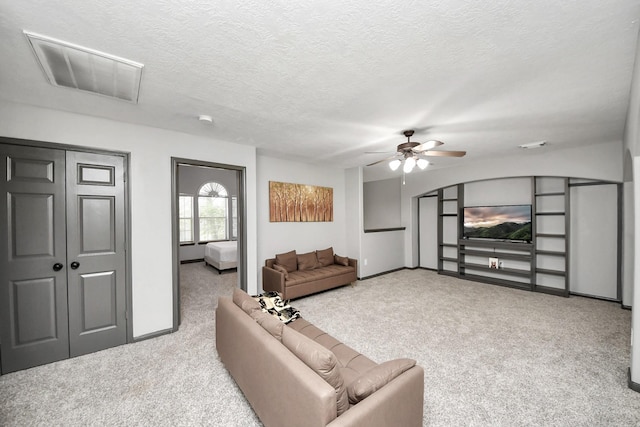 carpeted living area with visible vents, a textured ceiling, baseboards, and ceiling fan