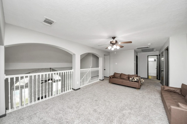 living area with visible vents, carpet, a textured ceiling, and ceiling fan