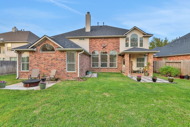 rear view of house with a fenced backyard, brick siding, and a patio