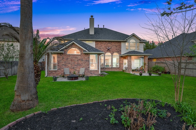 back of house at dusk featuring a fenced backyard, a chimney, and a patio area