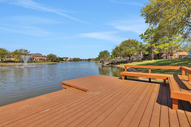 view of dock with a lawn and a water view