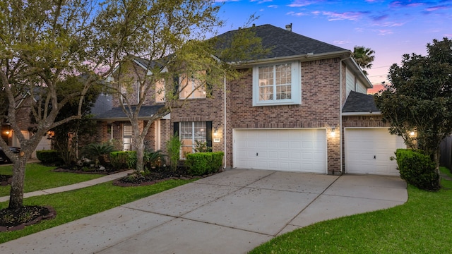 view of front of property with concrete driveway, roof with shingles, an attached garage, a front lawn, and brick siding