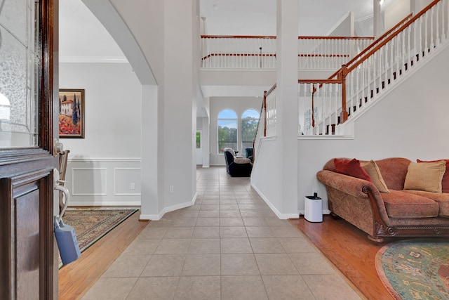 entrance foyer featuring stairway, a high ceiling, tile patterned flooring, arched walkways, and ornamental molding