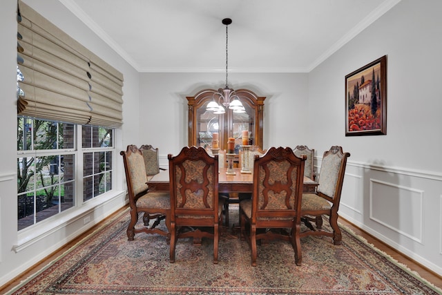 dining area with crown molding, wood finished floors, wainscoting, a decorative wall, and an inviting chandelier
