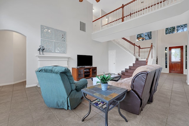 living area featuring visible vents, baseboards, stairs, a ceiling fan, and arched walkways
