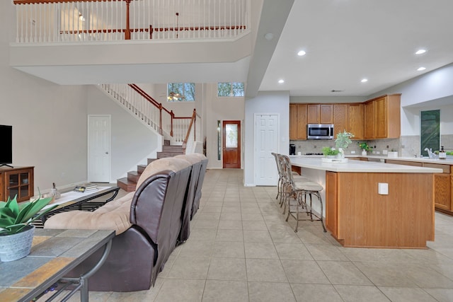 kitchen featuring light countertops, a high ceiling, a center island, open floor plan, and stainless steel microwave