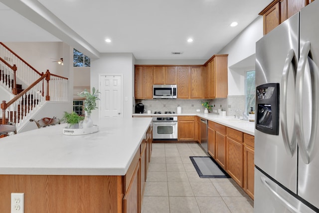 kitchen with light countertops, tasteful backsplash, light tile patterned floors, stainless steel appliances, and a sink