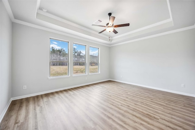 spare room featuring a tray ceiling, baseboards, ceiling fan, and wood finished floors