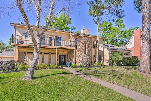 307 Crestwood Dr, El Lago, TX 77586 - view of front of home featuring stone siding, a balcony, a front yard, and a chimney