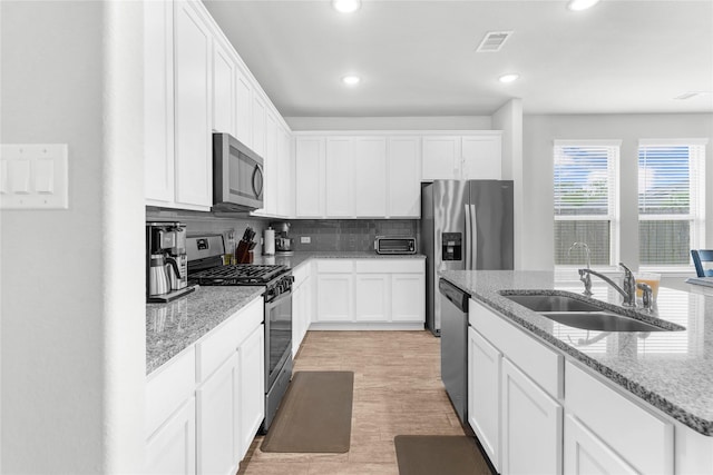 kitchen featuring white cabinetry, a sink, stainless steel appliances, and visible vents