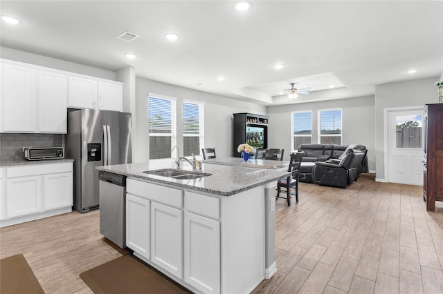 kitchen with light wood-style flooring, a ceiling fan, tasteful backsplash, appliances with stainless steel finishes, and a sink