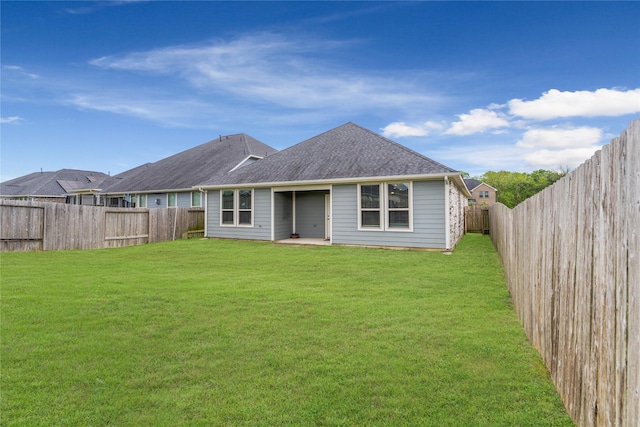 rear view of property with a fenced backyard, a lawn, and a shingled roof