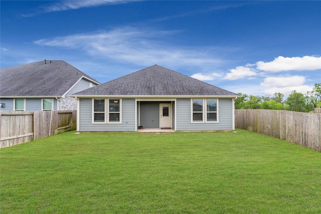 back of property with a fenced backyard, a shingled roof, and a lawn