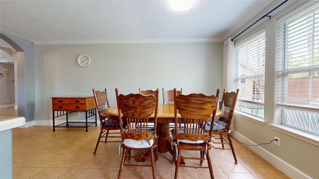 dining area featuring ornamental molding, light tile patterned flooring, arched walkways, and baseboards