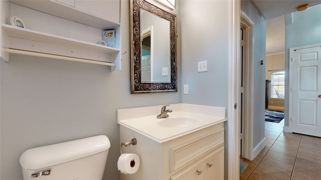 half bath with tile patterned flooring, vanity, toilet, and crown molding