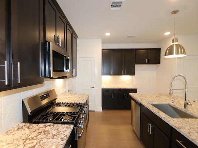 16208 Mcdonald County Ct, Montgomery, TX 77316 - kitchen featuring stainless steel appliances, a sink, tasteful backsplash, light stone countertops, and wood finished floors