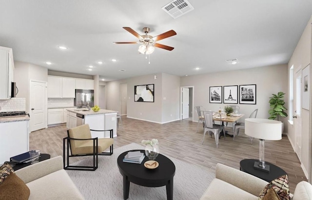 living room featuring recessed lighting, ceiling fan, visible vents, and light wood-style floors
