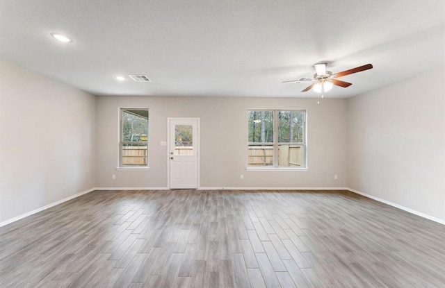 unfurnished living room featuring visible vents, baseboards, ceiling fan, and wood finished floors