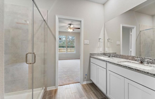 bathroom featuring wood finish floors, a sink, ceiling fan, and a shower stall