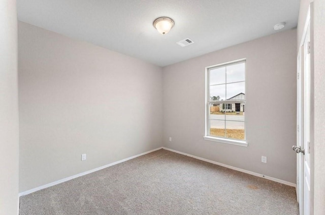 carpeted spare room featuring baseboards and visible vents