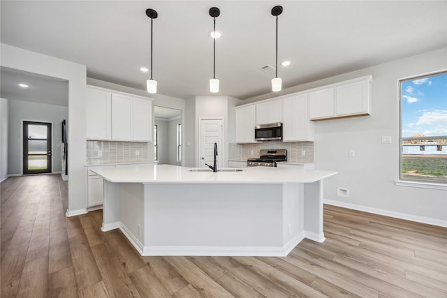 kitchen featuring light countertops, a sink, a large island with sink, and appliances with stainless steel finishes