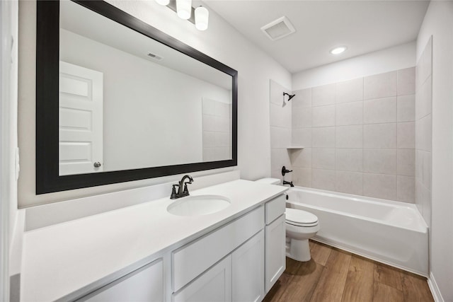 bathroom featuring toilet, vanity, shower / tub combination, wood finished floors, and visible vents