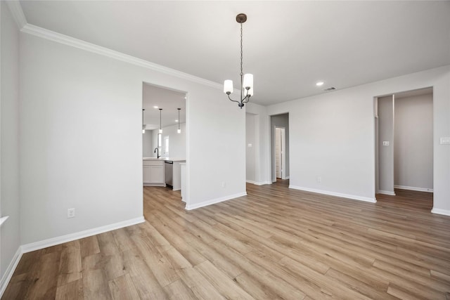 empty room with light wood finished floors, baseboards, a notable chandelier, and a sink
