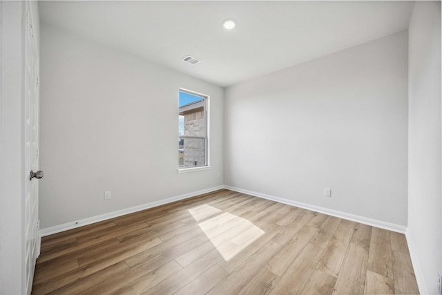 spare room featuring baseboards, light wood finished floors, and visible vents