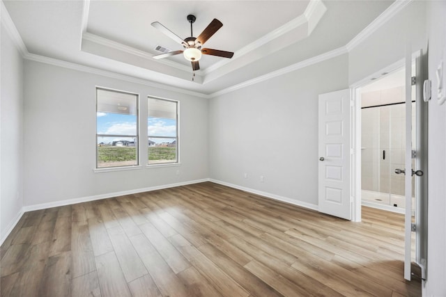 unfurnished bedroom with visible vents, crown molding, baseboards, wood finished floors, and a tray ceiling