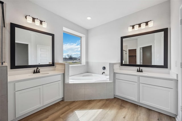 full bath featuring a sink, two vanities, and a garden tub