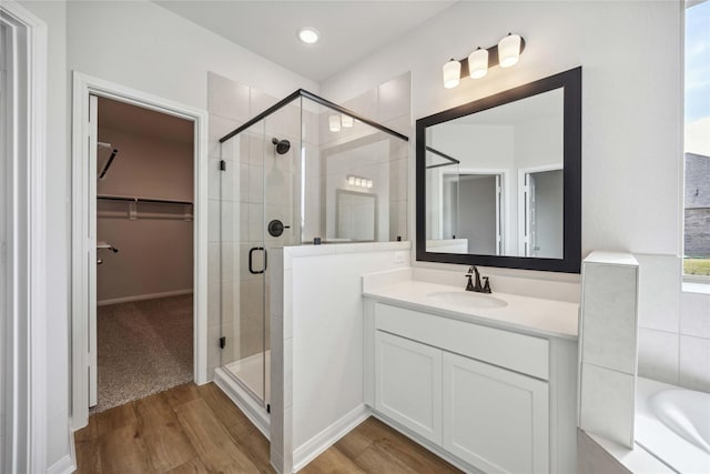 full bath with a stall shower, wood finished floors, vanity, and a walk in closet