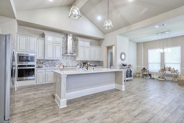 17473 Chestnut Cove Dr, Conroe, TX 77302 - kitchen featuring appliances with stainless steel finishes, wall chimney exhaust hood, light countertops, decorative backsplash, and pendant lighting