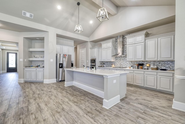 17473 Chestnut Cove Dr, Conroe, TX 77302 - kitchen with stainless steel fridge, wall chimney range hood, gas stovetop, light countertops, and decorative backsplash