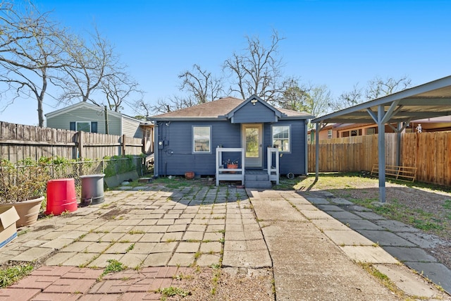 rear view of property featuring a fenced backyard, roof with shingles, and a patio area