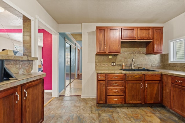 413 Mulcahy St, Rosenberg, TX 77471 - kitchen featuring light countertops, a sink, brown cabinets, baseboards, and decorative backsplash